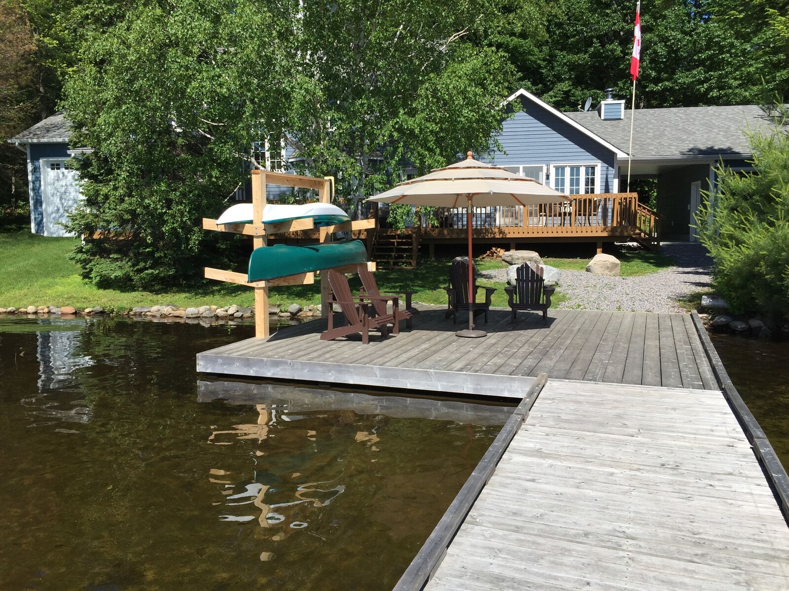 The Baypoint dock with kayaks, canoe, Adirondack chairs and the cottage behind.